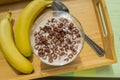 Bowl of oatmeal chocolate flakes in the shape of letters of the alphabet with milk on a wooden tray with bananas, healthy Royalty Free Stock Photo