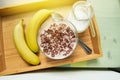 Bowl of oatmeal chocolate flakes in the shape of letters of the alphabet with milk on a wooden tray with bananas and a jug of milk Royalty Free Stock Photo