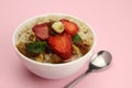 Bowl of oatmeal with fruit on a pink background. Healthy breakfast