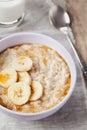 Bowl of oatmeal porridge with banana and caramel sauce on rustic table, hot and healthy breakfast Royalty Free Stock Photo