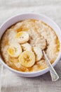 Bowl of oatmeal porridge with banana and caramel sauce on rustic table, hot and healthy breakfast Royalty Free Stock Photo