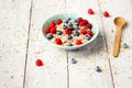 Bowl of oatmeal porridge with blueberry and raspberries on white table with honey and milk. Top view in flat lay style Royalty Free Stock Photo