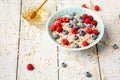 Bowl of oatmeal porridge with blueberry and raspberries on white table with honey and milk. Top view in flat lay style Royalty Free Stock Photo