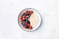 Bowl of oatmeal porridge with blueberry and raspberry on white table top view. Yummy and diet breakfast