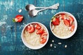 Bowl of oatmeal porridge with strawberry and almond flakes on rustic teal table top view in flat lay style. Healthy breakfast.