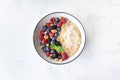 Bowl of oatmeal porridge with various berry and nuts on white table top view. Healthy and diet breakfast