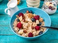 Bowl of oatmeal with raspberries and blueberries on a blue wooden table. Royalty Free Stock Photo