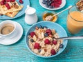 Bowl of oatmeal with raspberries and blueberries on a blue wooden table. Royalty Free Stock Photo