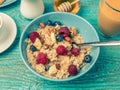 Bowl of oatmeal with raspberries and blueberries on a blue wooden table. Toned photo. Royalty Free Stock Photo