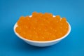 Bowl of Orange Popping Boba Pearls on Bright Blue Background