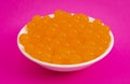 Bowl of Orange Popping Boba Pearls on Bright Pink Background