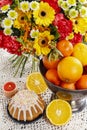 Bowl of oranges and bouquet of gerbera and carnation flowers