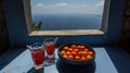 a bowl of oranges and a glass of water on a table with a view of the ocean from a window in a house on the island