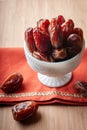 A bowl of organic medjool dates on an embroidered orange cloth.