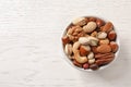 Bowl with organic mixed nuts on white wooden background, top view. Royalty Free Stock Photo