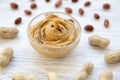 Bowl of peanut butter with peanuts over white wooden background, close-up. Royalty Free Stock Photo
