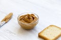 Bowl of peanut butter, toast and knife over white wooden background, Royalty Free Stock Photo