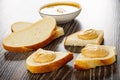Bowl with peanut paste, slices of bread, sandwiches with peanut butter on wooden table