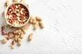 Bowl with peanuts on white textured background