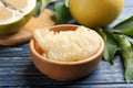 Bowl with peeled pomelo slices on blue wooden table, closeup