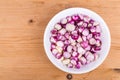 Bowl of peeled shallots onion and garlic on wooden table