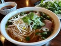 A bowl of pho with herbs, bean sprouts, and broth, served with a side of dipping sauce Royalty Free Stock Photo