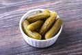 Bowl with pickled gherkins, cucumbers on wooden background close up. Pickles.