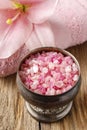 Bowl of pink sea salt and lily flower in the background Royalty Free Stock Photo