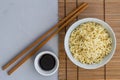 Bowl of plain cooked noodles with chopsticks and little bowl of soy sauce - top view