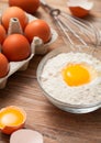 Bowl plate with flour and egg yolk on wooden background with fresh raw eggs and metal whisk Royalty Free Stock Photo