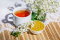 A bowl of pollen and aromatic herbal tea. Still life in a rustic style with a branch and flowers of a bird cherry and