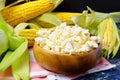 A bowl of popcorn with cobs of fresh corn on a dark background. Leisure. Royalty Free Stock Photo