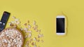 Bowl of popcorn, remote control and mobile phone on yellow background.