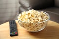 Bowl of popcorn and TV remote on table