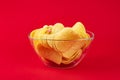 Bowl of potato chips in bright red background. Minimalistic image of attention grabbing fast food in vivid colors Royalty Free Stock Photo