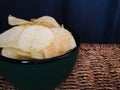 A bowl of potato chips in a green bowl on rattan table close up Royalty Free Stock Photo