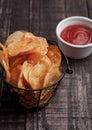 Bowl with potato crisps chips and ketchup on wooden board Royalty Free Stock Photo