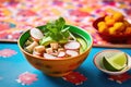 a bowl of pozole with radishes, lettuce, and avocado slices, colorful backdrop Royalty Free Stock Photo