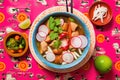 a bowl of pozole with radishes, lettuce, and avocado slices, colorful backdrop Royalty Free Stock Photo