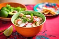 a bowl of pozole with radishes, lettuce, and avocado slices, colorful backdrop Royalty Free Stock Photo