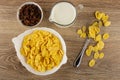 Bowl with raisin, pitcher with yogurt, corn flakes in bowl, flakes and spoon on table. Top view Royalty Free Stock Photo