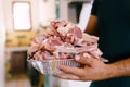 A bowl of raw lamb ribs, sliced for grilling, in the male hands of the chef.