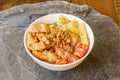 Bowl with raw salmon, pineapple chunks, tempura vegetables and fried onion