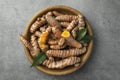 Bowl with raw turmeric roots and green leaves on grey table, top view Royalty Free Stock Photo