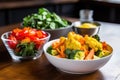 a bowl of raw vegetables next to a plate of fried food