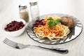 Bowl with red beans, salt and pepper, plate with spaghetti, cutlet, beans, parsley, fork on wooden table