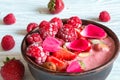 Bowl of red berry smoothie with strawberry, raspberry, nuts and seeds decorated with rose flower petals Royalty Free Stock Photo