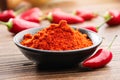 Bowl of red chili pepper ground to powder and whole red hot pepper pods on background