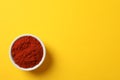 Bowl with red pepper powder on yellow Royalty Free Stock Photo
