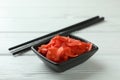 Bowl with red pickled ginger and chopsticks on white wooden background Royalty Free Stock Photo